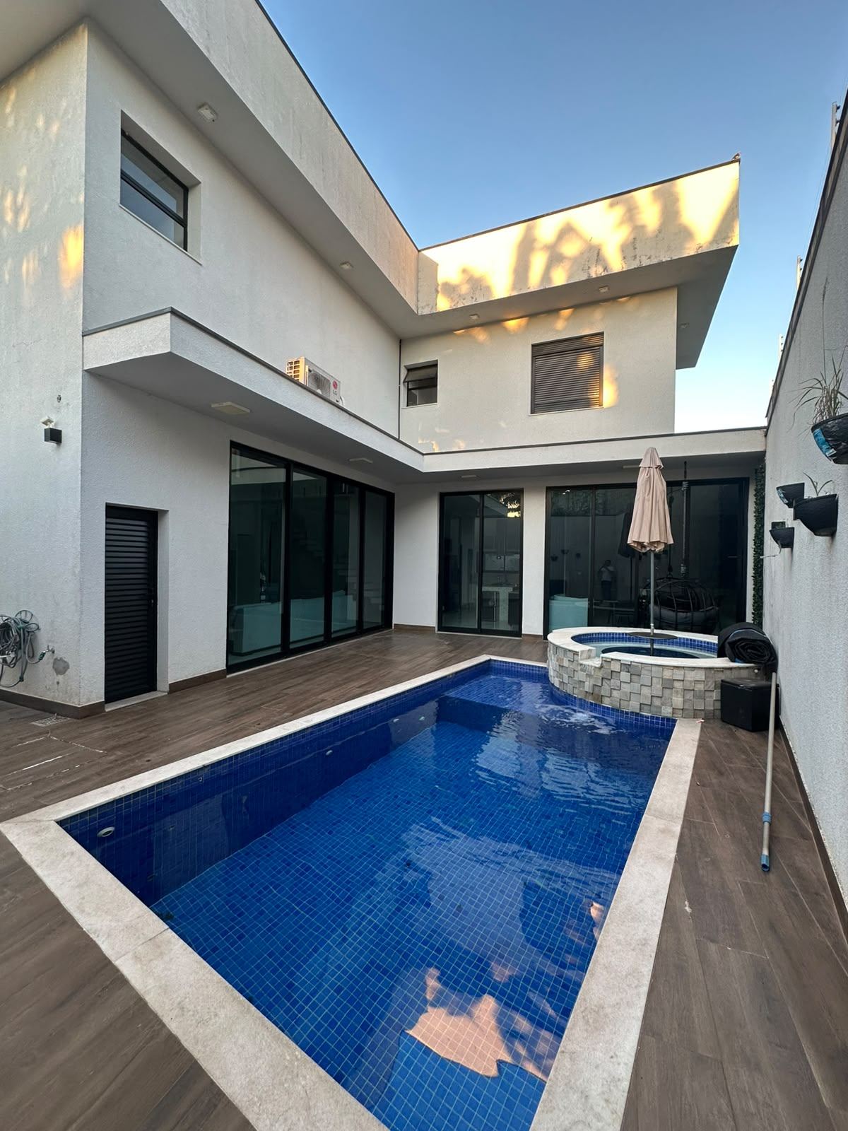 Piscina azul com hidromassagem e deck de madeira
